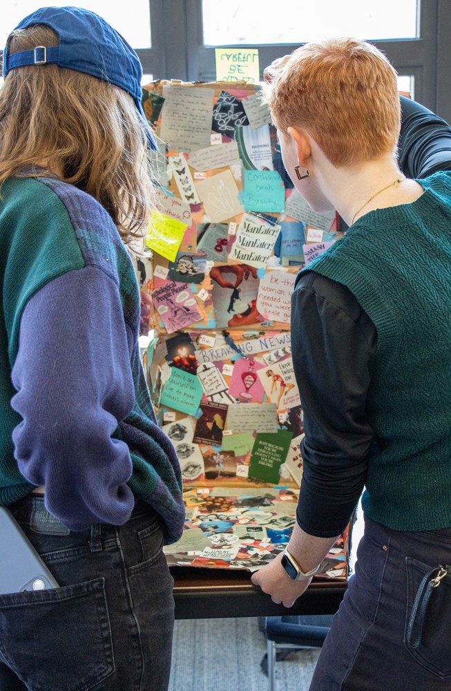 two students look at large collage art work