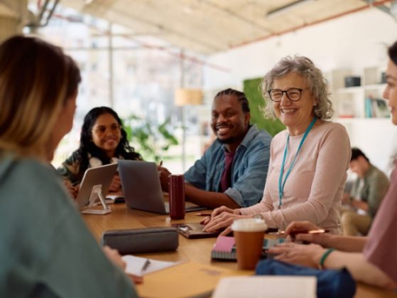Happy university teacher communicating with her students in classroom.
