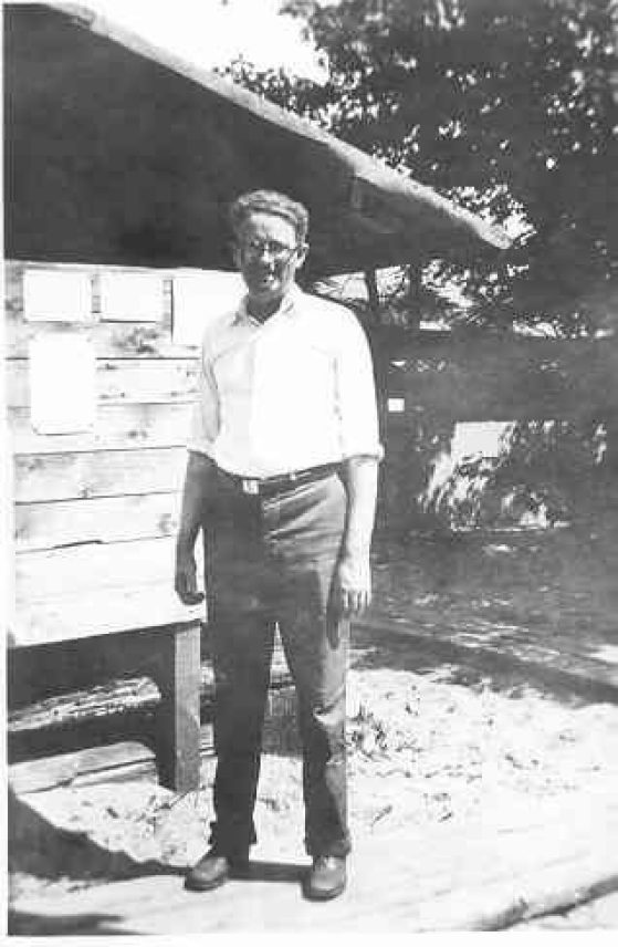 Black and white photo of a man standing next to a building