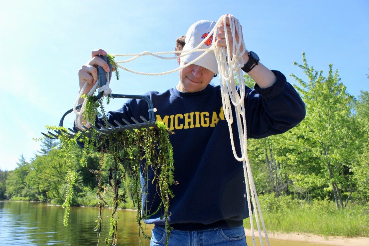 Person holding a rake with algae on it