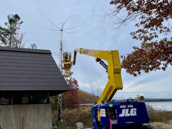 People on a lift machine putting up an antenna on a tower