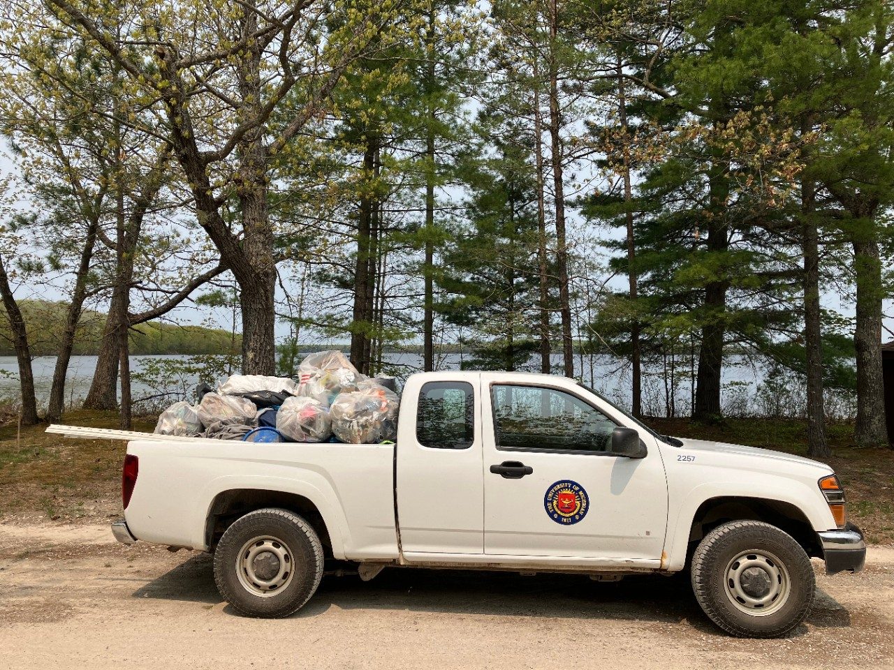 Truck loaded with bags of garbage along a lake