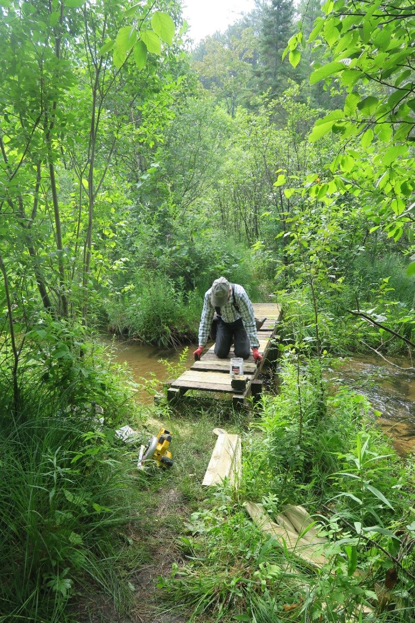 Man building a wooden trail over a creek