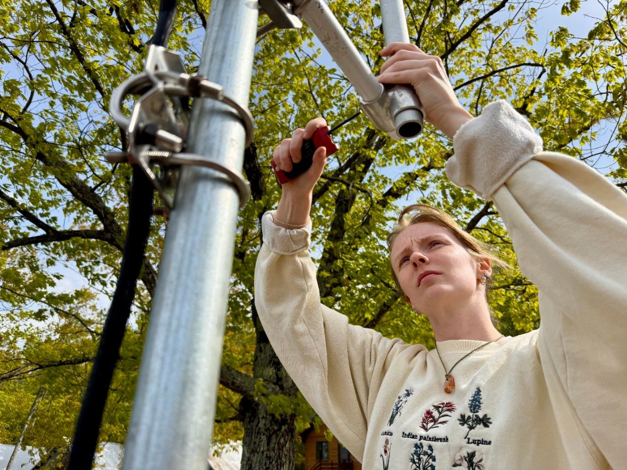 Woman uses a tool to attach a part to a tower