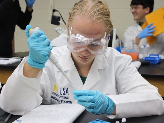 Person wearing safety goggles using scientific instrument in laboratory