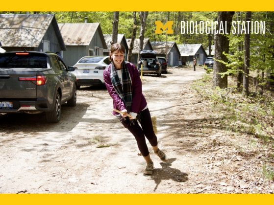 Person dancing outside on a forest next to cabins and cars