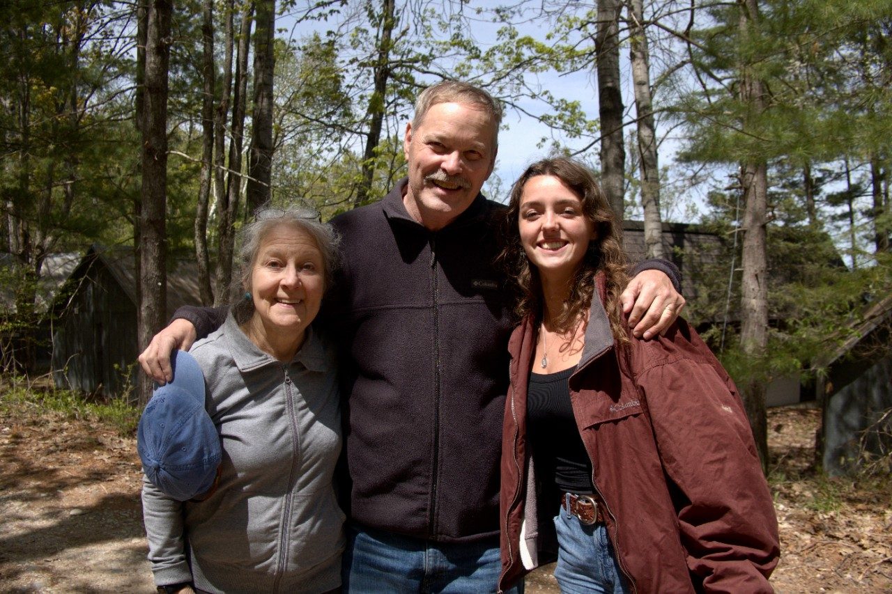 Three people posing for a picture in the woods