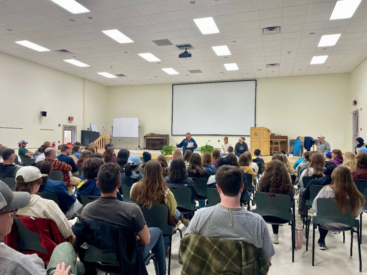 Person speaking in a lecture hall to a group of seated people