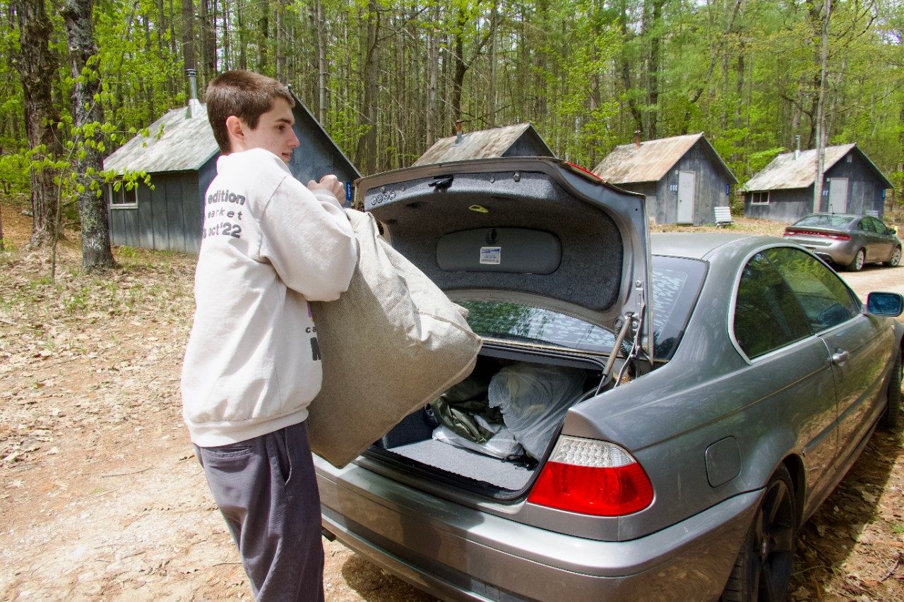 Person unloading a bag from the trunk of a car