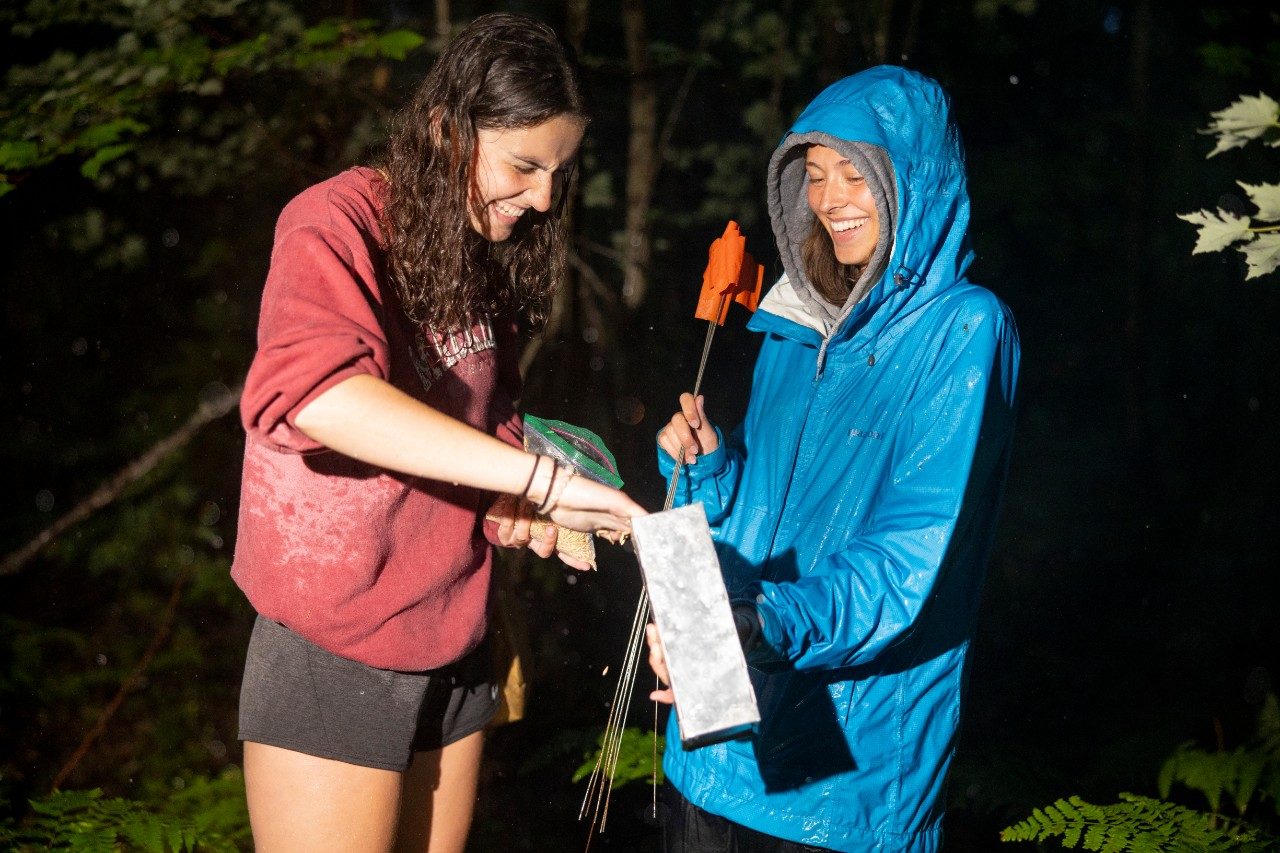 Two people in the woods at night looking at a live trap