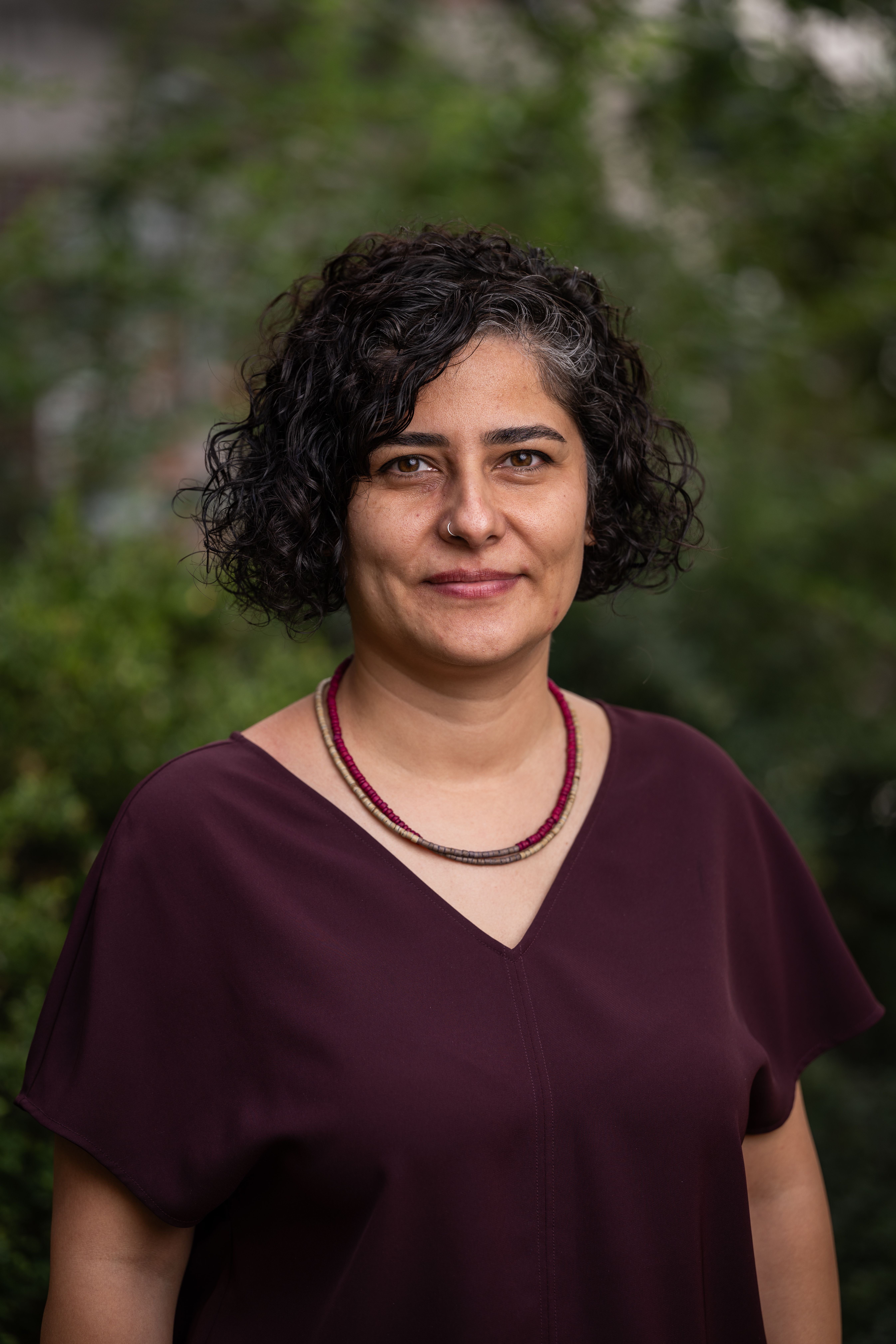 Seda Saluk in a red shirt against a green leafy background