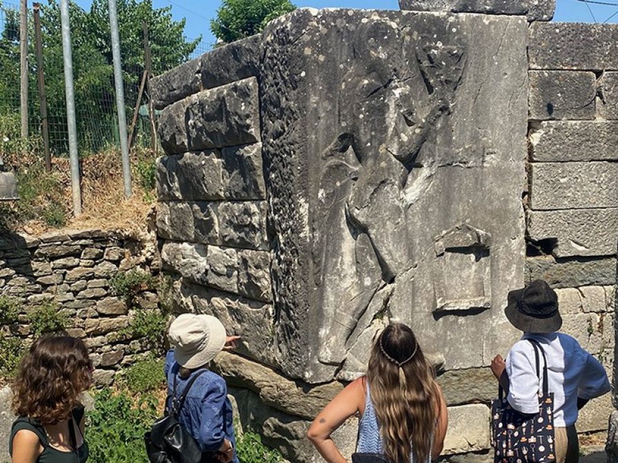 Prof. Lisa Nevett and three students standing in front of the ancient stone gate of the city Thasos