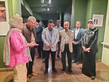 Five people (Janet Richards, Moamen Osman, Ahmed Hemayda, Alaa El Qadi, and Nahla Abdullah El Keshky stand in a group talking in the Weni the Elder exhibit gallery space.