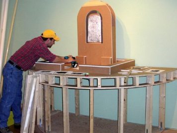 Kelsey Museum staff member Scott Meier uses a drill to assemble a model of a votive context.