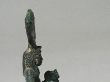 Corroded bronze statuette of the goddess Isis, holding the child Horus.