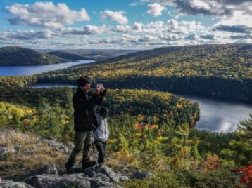 Two people against a dramatic backdrop of trees, water, and sky.