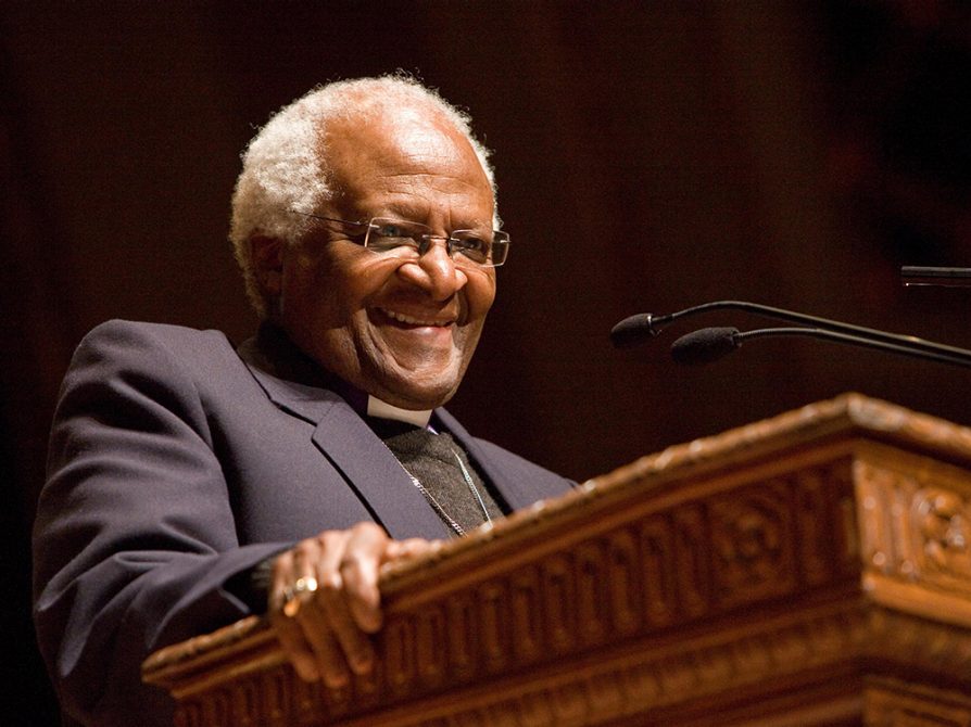 Desmond Tutu smiles at a podium.
