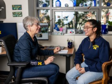 Student and advisor converse in a brightly lit office