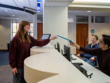 Newnan staff hand student a file in advising center