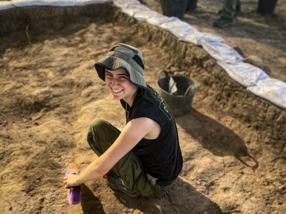 Welch working in an excavation site with a purple brush and basket.