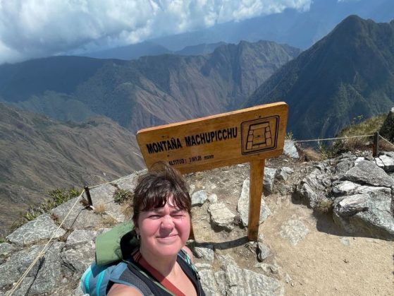 Taking a selfie at the lookout over Machu Picchu in front of a sign that reads, "MONTAÑA MACHUPICCHU, ALTITUD: 3 061.28 msnm