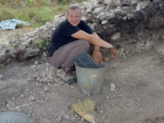 Densel squatting, with a bucket and tools, working alongside an exposed wall of an elite residence.