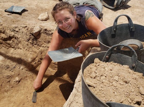 Tutak working in a shallow excavation hole with bags of excavated soil on the rim.