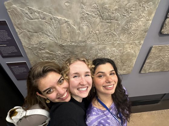 Three colleagues take a selfie in front of a carved piece of stone.