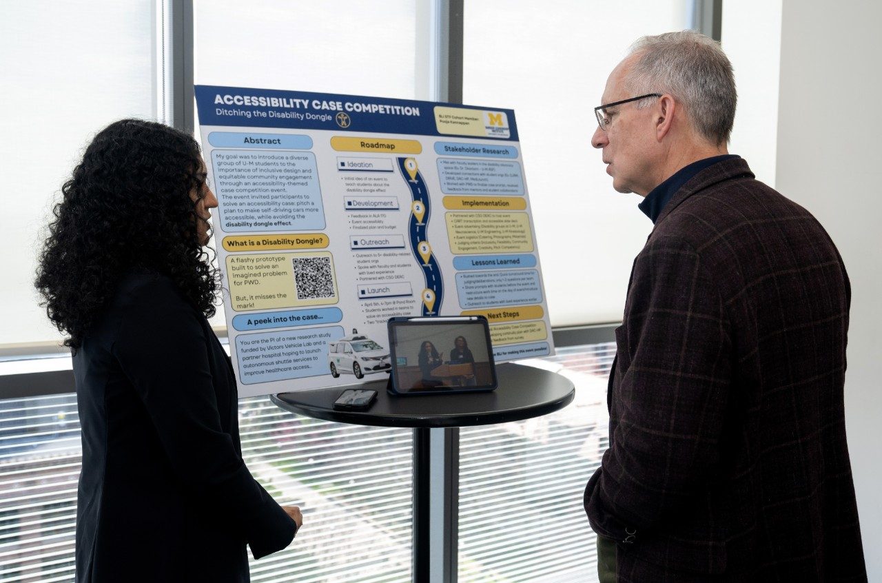 Student talking with person about their poster presentation.