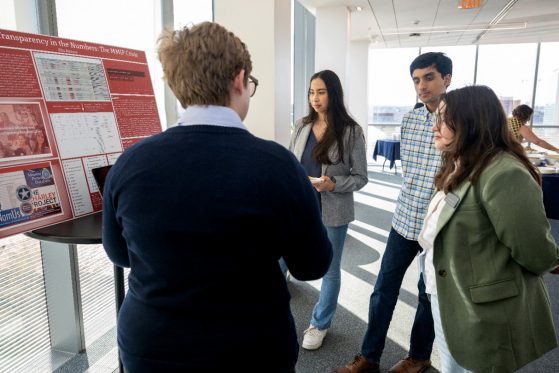 Student talking with people about their poster presentation.