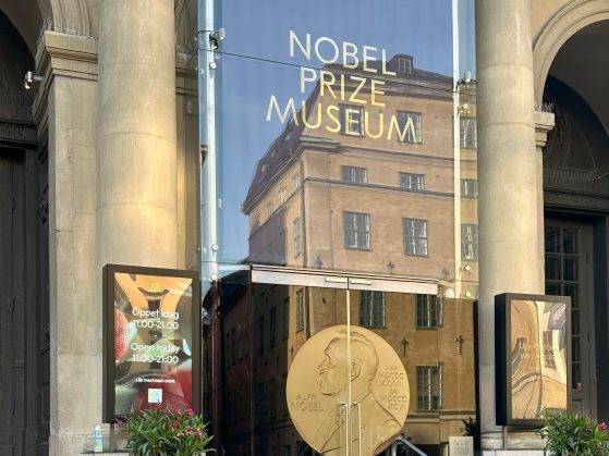 Nobel Prize Museum, Stockholm, Sweden. Pictured: Prema. Caption: Prema standing in from the the doors for the Nobel Prize Museum, an area highlighting the history, the founder, and the various discoveries of Nobel Prize Winners