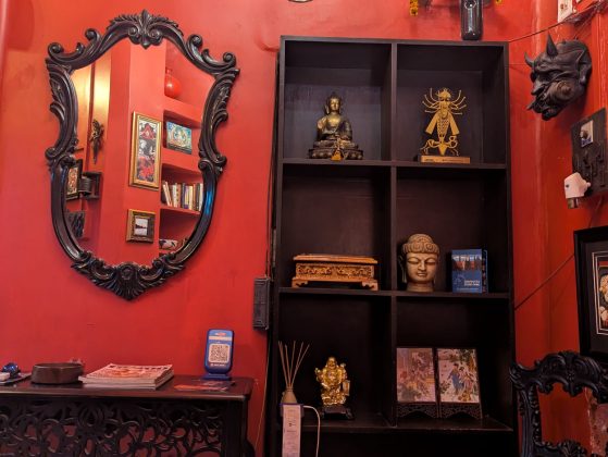 Image of the tattoo parlor, with a red wall, shelf, and mirror pictured