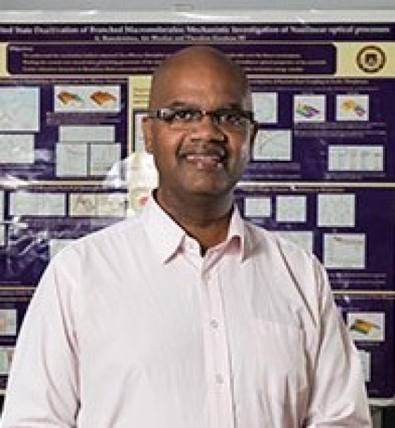 an African American man in a white shirt standing in front of a scientific poster