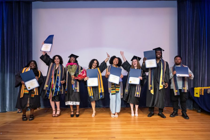 2025 DAAS graduates pose onstage with their diplomas after the ceremony.