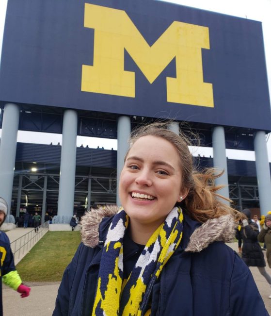 Emily is pictured in front of a U-M sign at the Big House