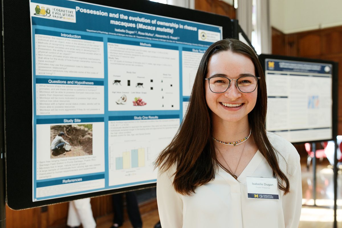 Isabelle poses in front of the poster, smiling 