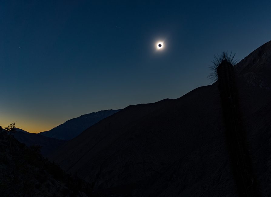 The moment of totality, solar eclipse along the ruta de las estrellas, in the high desert, Paihuano, Coquimbo, Chile. Image credit: Rumaan Malhotra. Mountain outline in foreground, total solar eclipse in dark blue sky 