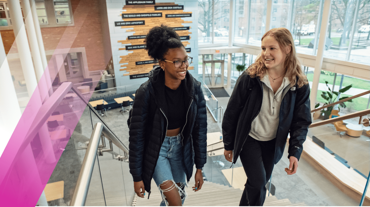LSA Scholarship recipients, Victoria Derricks (left) and Eve Martin (right), ascend the central stairway in the LSA building addition with its floor to ceiling donor recognition wall visible in the background.