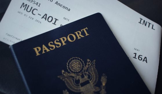 A photograph of a passport on top of a plane ticket.