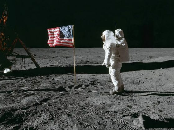 A photo of Neil Armstrong and a United States flag on the moon during the first moon landing in 1969.