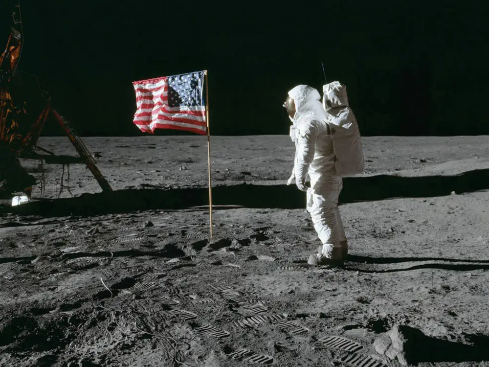 A photo of Neil Armstrong and a United States flag on the moon during the first moon landing in 1969.