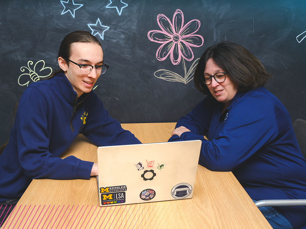 Alan and Linda, a son and mother, sit at a table with a laptop between them.