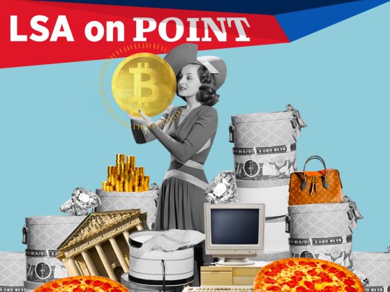 A woman holding a large gold coin with the letter B standing amid hat boxes, diamonds, and packaging from a shopping spree, pizzas, and a computer monitor.