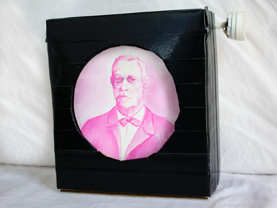 A photograph of a layered black square with a round cutout that features a pink image of a man in 19th century dress -- a Victorian cravat and jacket -- wearing small spectacles