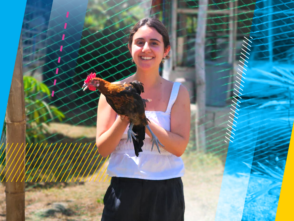 Samantha Dell’Imperio holding up a chicken while smiling. 