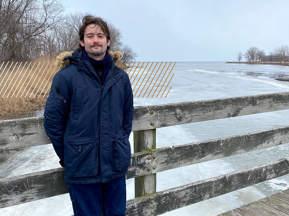  A person in a blue winter coat stands in front of a frozen pond. 