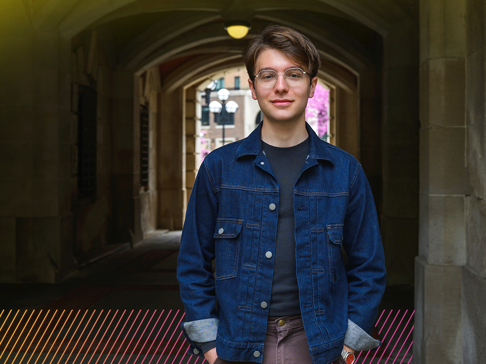 A person wearing glasses stands in front of an archway.