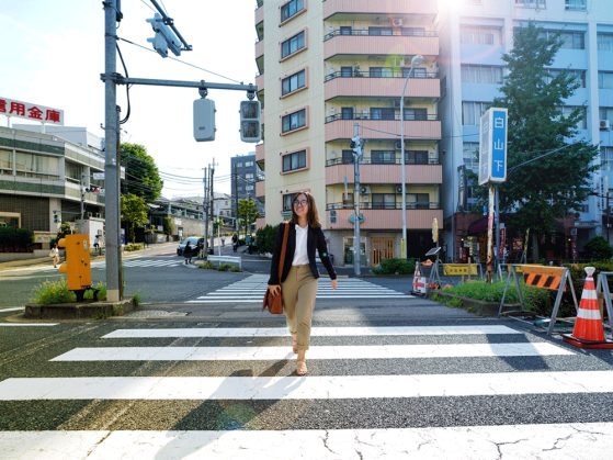 Hannah Dang walking through a crosswalk in a large city carrying a briefcase.