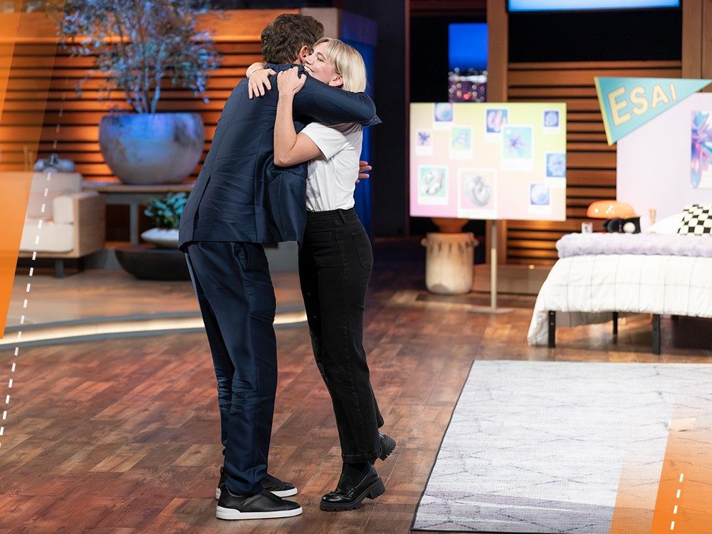 Two people hug on the set of a TV show.