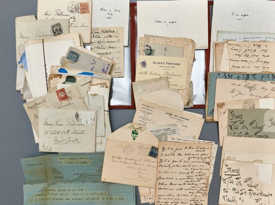 About thirty handwritten letters -- some in envelopes, some not -- arranged across a table. 